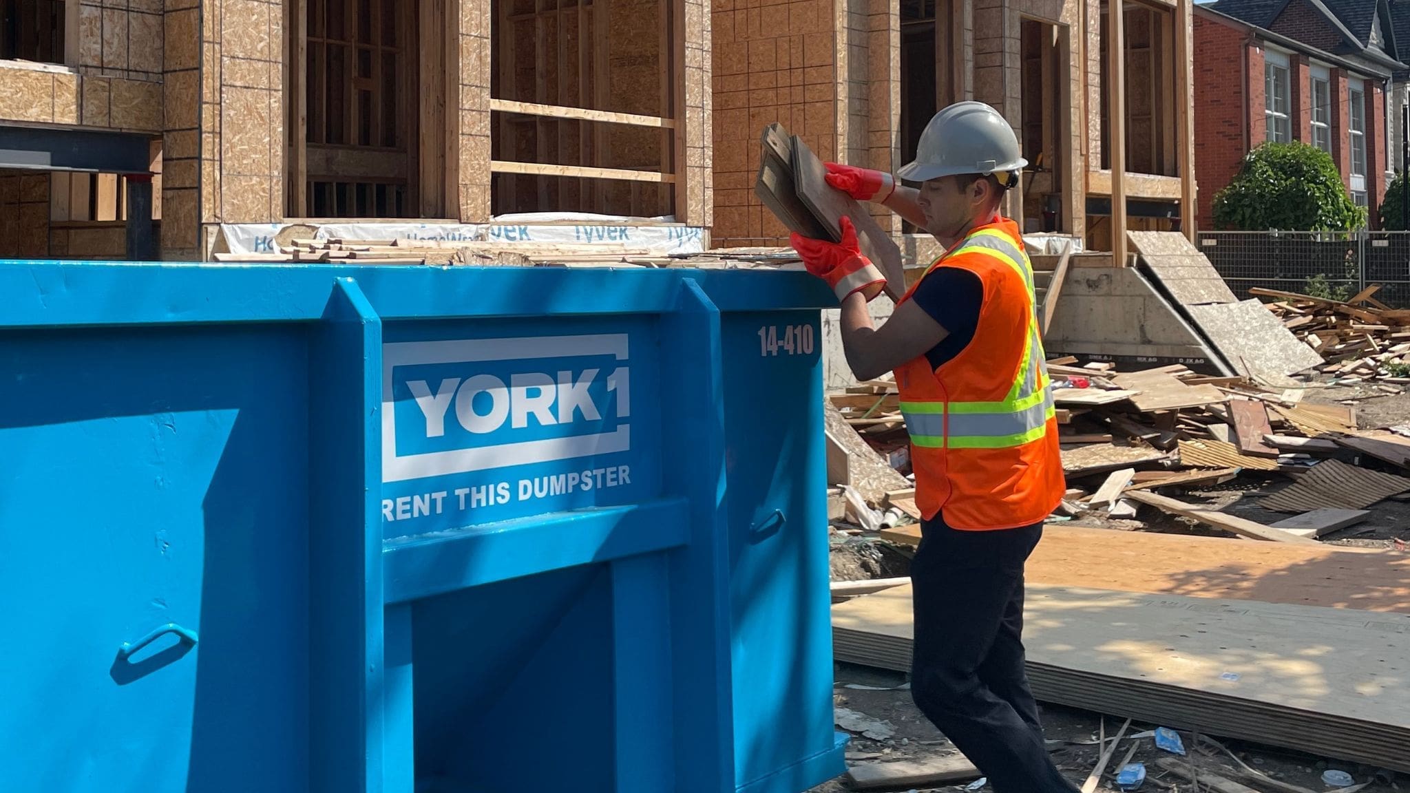 Construction worker removing debris into dumpster bin